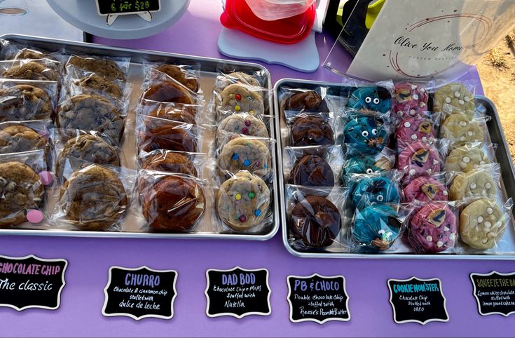 Cookies displayed at a farmers market on silver sheet pans in rows with chalkboard labels Bakers Market Stall, Farmers Market Cookies Display, Baked Goods Market Stall, Baking Vendor Booth Ideas, Easy Food Vendor Ideas, Cookies Farmers Market, Cookies For Farmers Market, Dessert Farmers Market, Snacks To Sell At Farmers Market