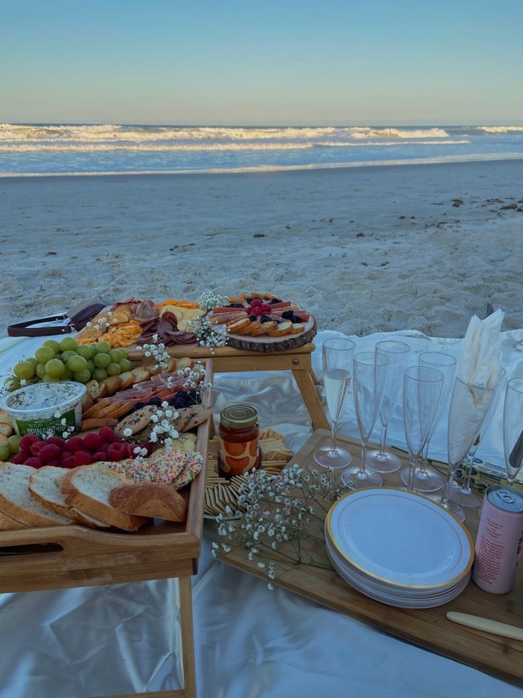 an assortment of food is laid out on a table at the beach, ready to be served