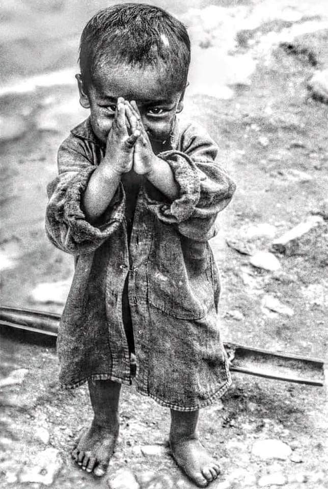 a little boy standing on the ground with his hands in front of his face and eyes closed