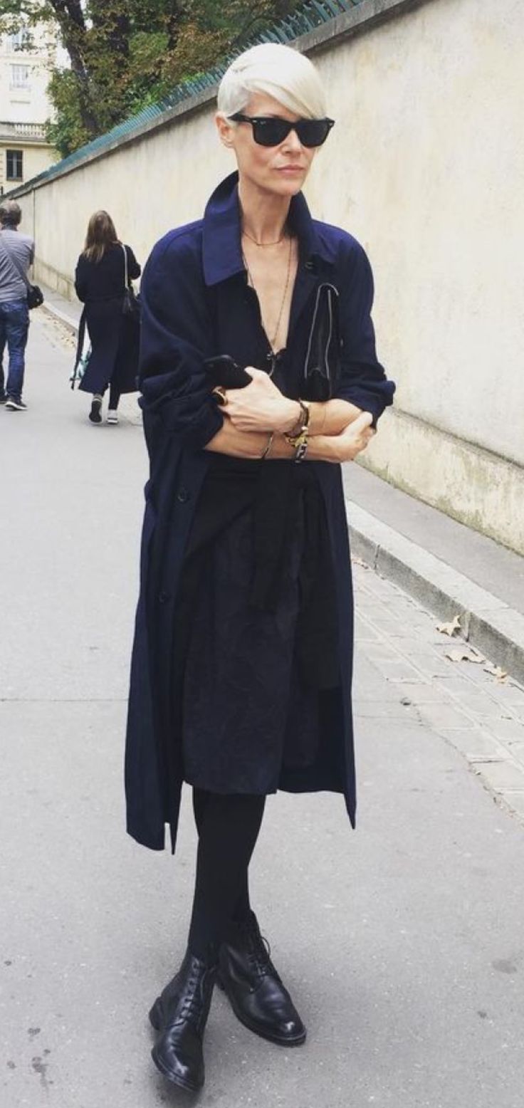 a woman in black is standing on the street