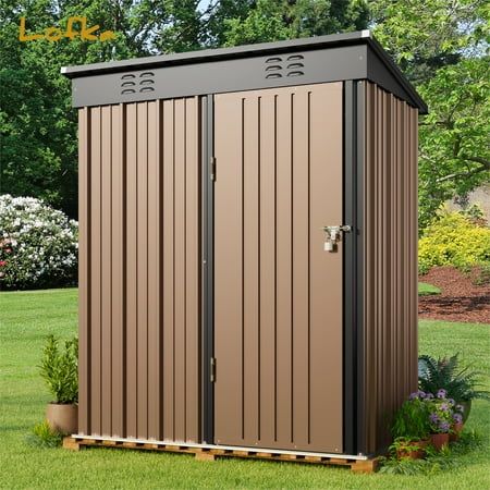 a brown storage shed sitting on top of a lush green field