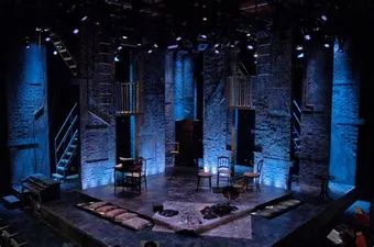 an empty stage with chairs and tables lit up by blue lights in the dark room