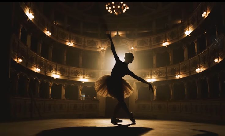 a ballerina in the middle of a stage with her arms up and legs spread out