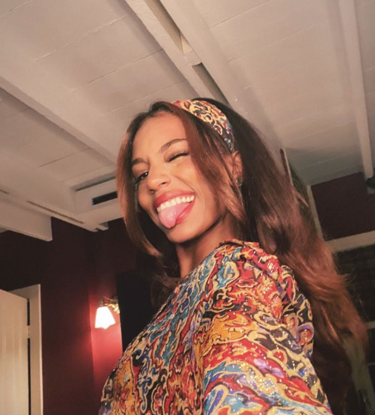 a woman with long hair wearing a colorful shirt and headband smiling at the camera