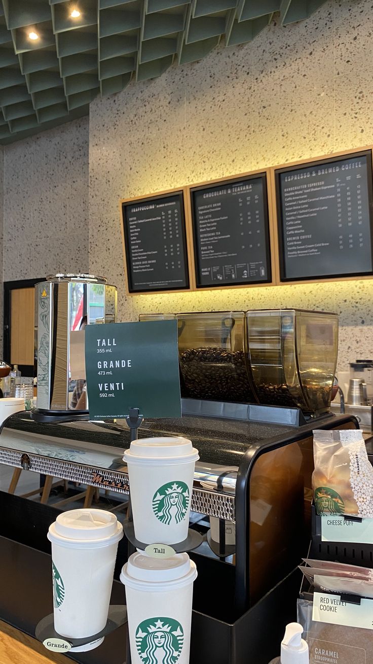 starbucks coffee cups are lined up on the counter in front of some menus and drinks