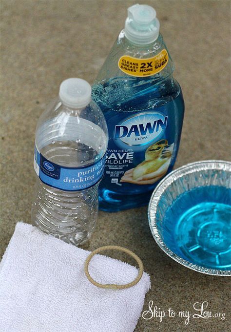 a bottle of dawn water next to a bowl of blue liquid and a white towel