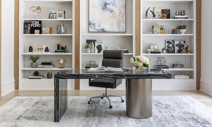 an office with white shelving and black leather chair in front of a marble topped desk