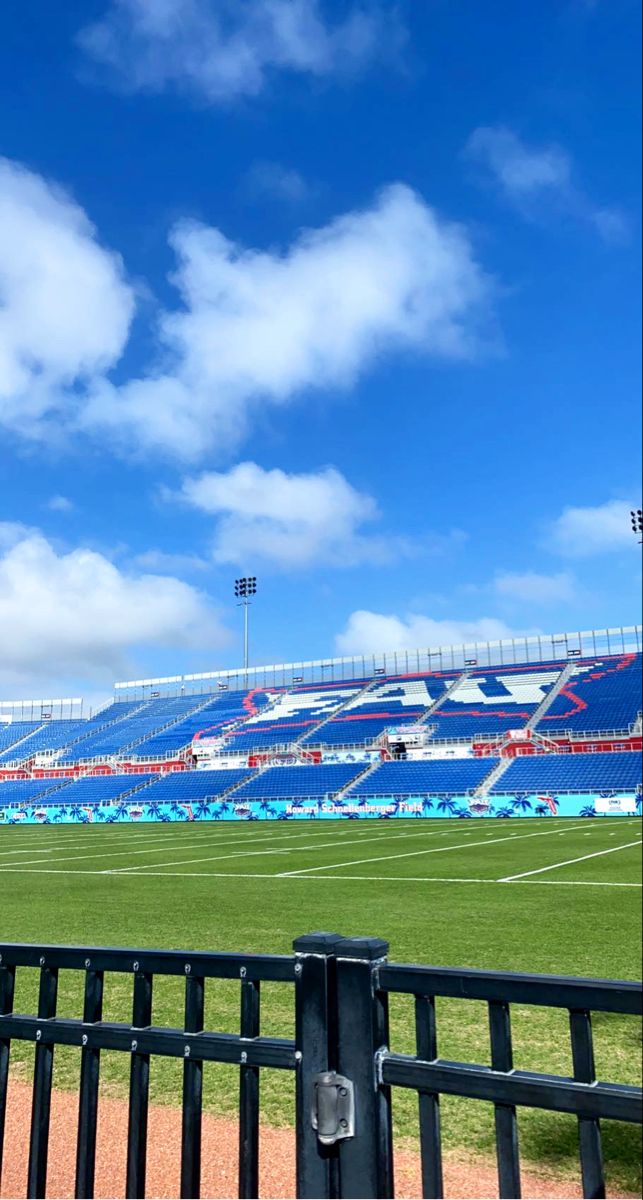 an empty soccer field with blue sky and clouds