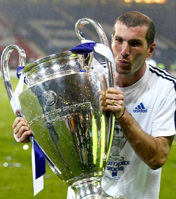 a man holding up a soccer trophy on top of a field