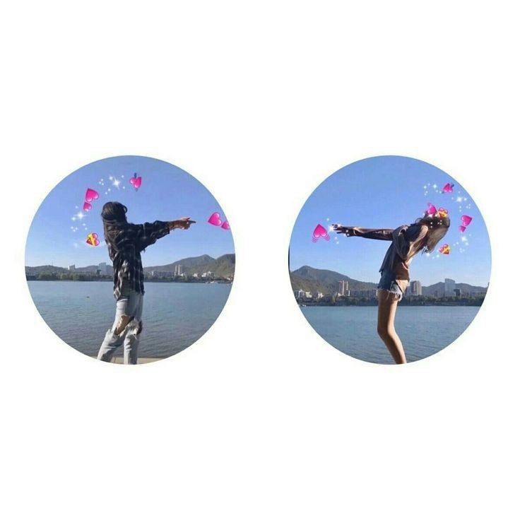 two people standing in front of a body of water with kites flying above them