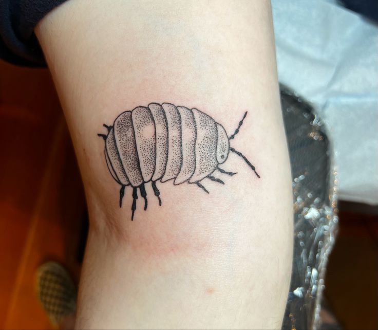 a black and white photo of a bug tattoo on the leg