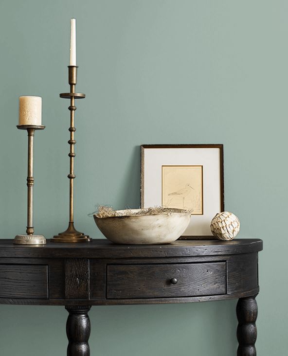 a wooden table with two candles and a bowl on it next to a candle holder