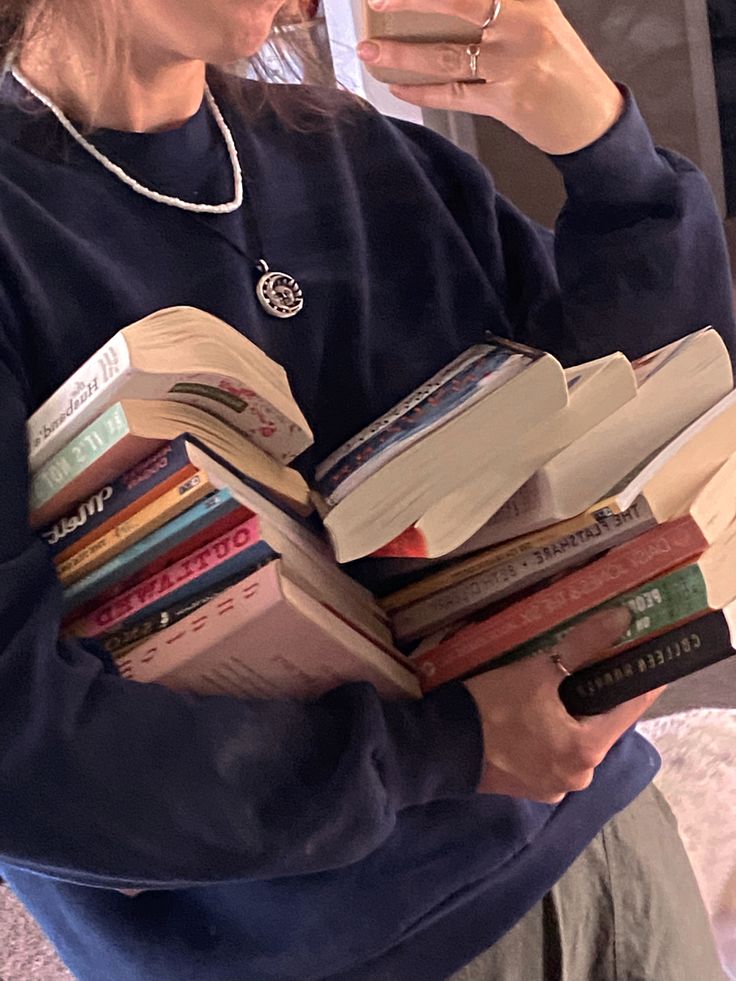 a woman holding a stack of books in her hands