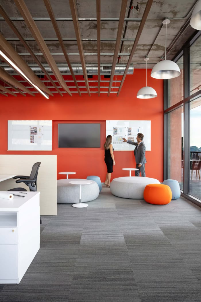 two people are standing in an office with orange walls and gray carpeted flooring