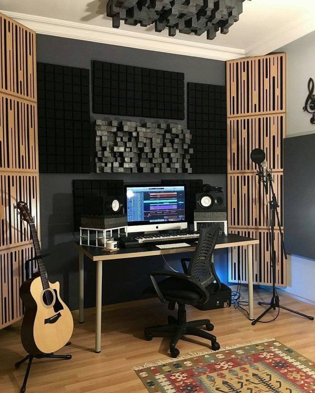 a room with a desk, guitar and sound board on the wall next to it