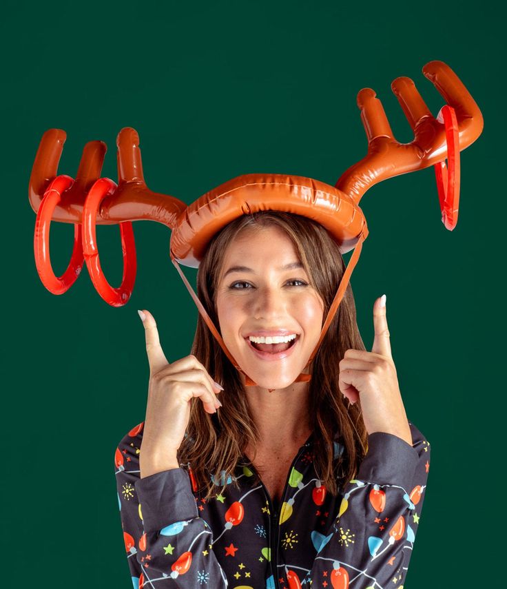 a woman is holding up two sausages in the shape of antlers on her head