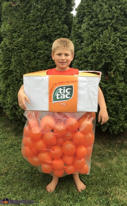 a young boy in an orange shirt is holding a box full of tomatoes