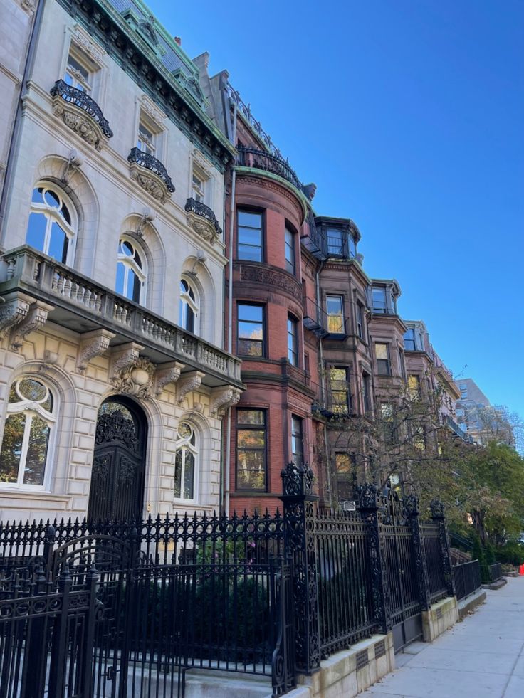 a row of browns and white buildings with black iron fences on the sidewalk in front of them