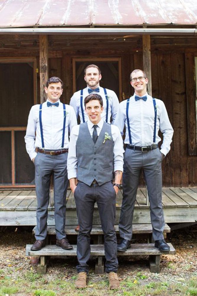 a group of men standing next to each other in front of a wooden building with a metal roof