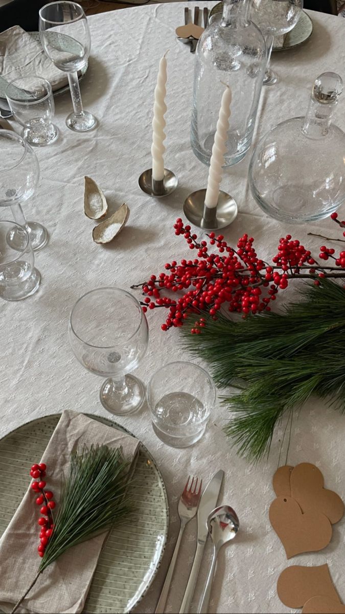 the table is set with silverware and red berries