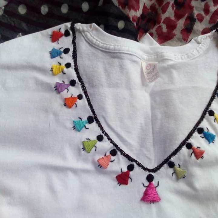 a white shirt with multi colored pom poms hanging from it's collar