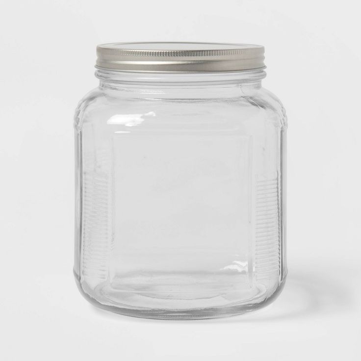 a clear glass jar with a metal lid on a white background, it is empty and ready to be used for storage