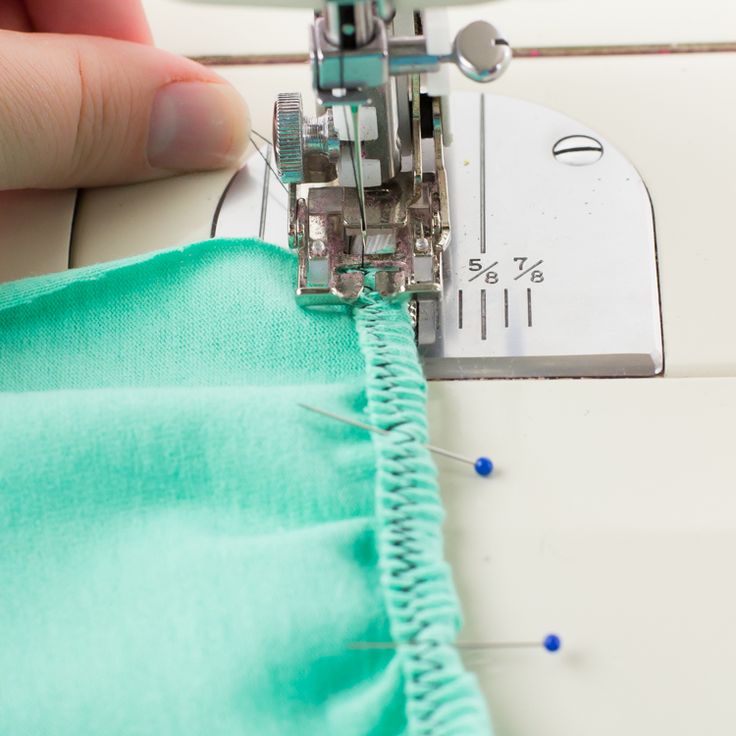 someone is using a sewing machine to sew on the green material that has been stitched together