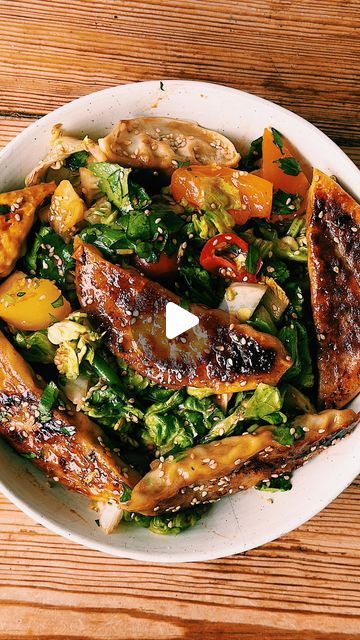 a white bowl filled with meat and vegetables on top of a wooden table next to a fork