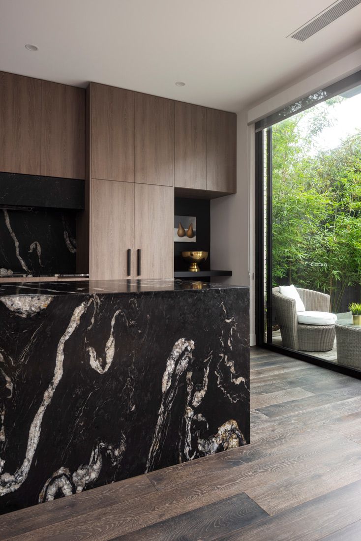 a large kitchen with marble counter tops and wooden cabinetry next to a sliding glass door