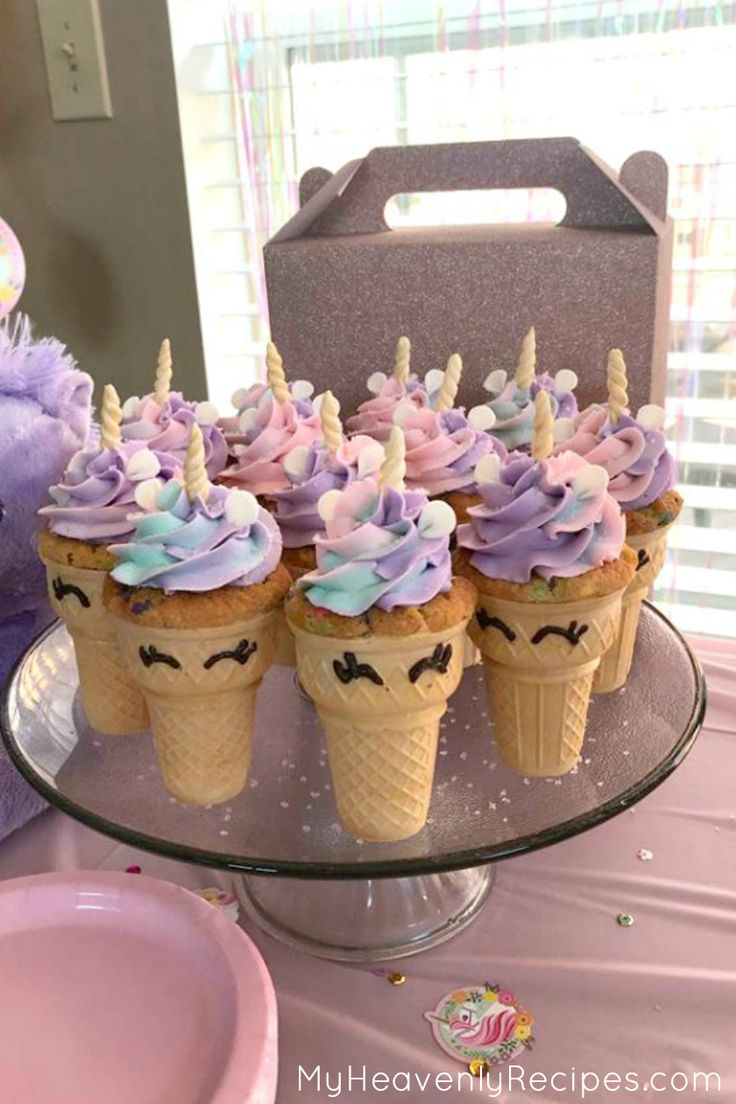 there are cupcakes with purple frosting and unicorn decorations on top of them