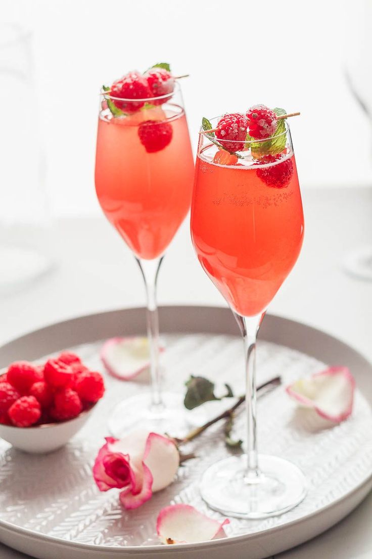 two wine glasses filled with raspberries on a tray