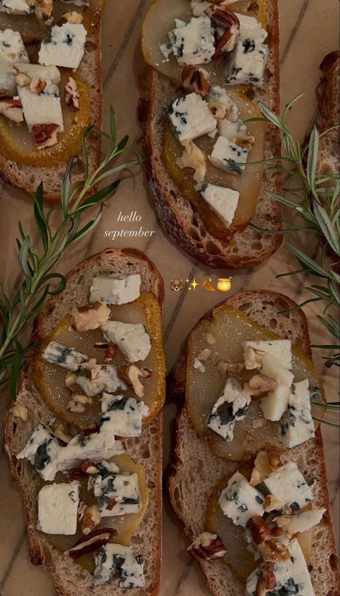 four slices of bread with cheese and vegetables on them, sitting on a table top