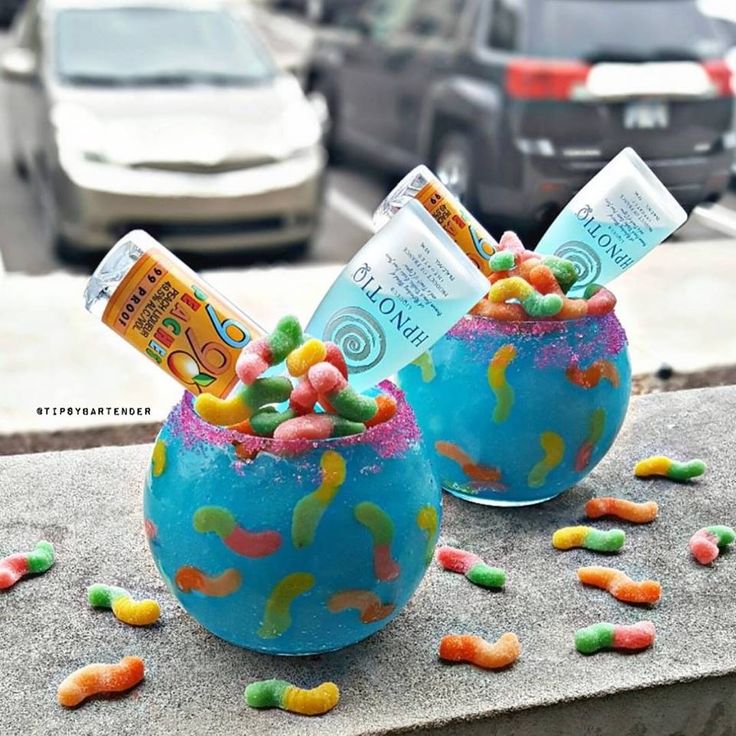 two bowls filled with candy sitting on top of a cement slab next to a street