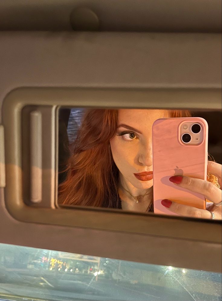 a woman taking a selfie with her phone in the back seat of a car