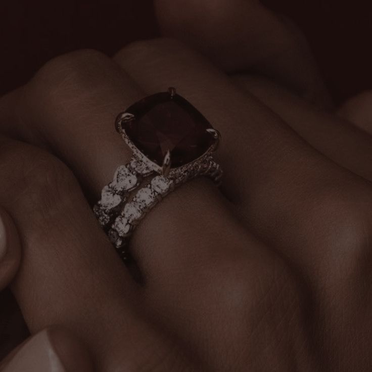 a woman's hand holding an engagement ring with a large brown stone surrounded by small white diamonds