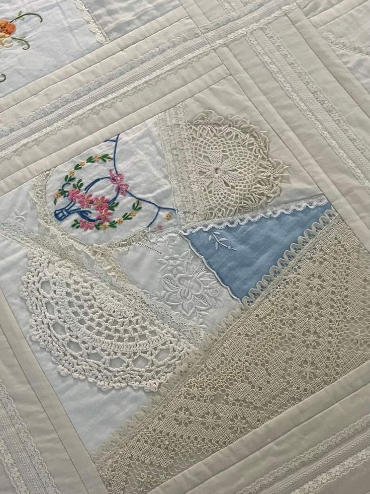 a close up of a quilt on a bed with white crocheted doily