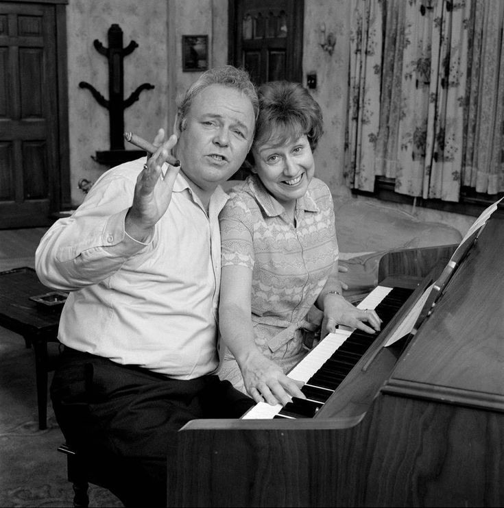 a man and woman sitting next to each other at a piano with their fingers in the air