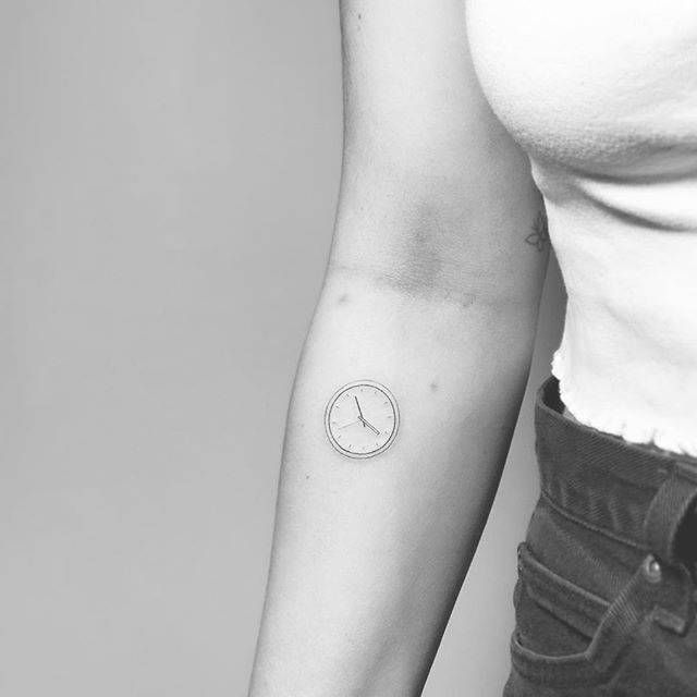 a woman with a small clock tattoo on her arm