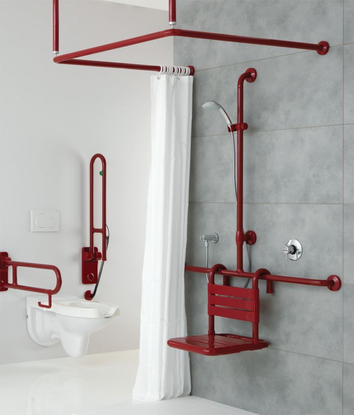 a white toilet sitting next to a shower in a bathroom with red fixtures on the wall