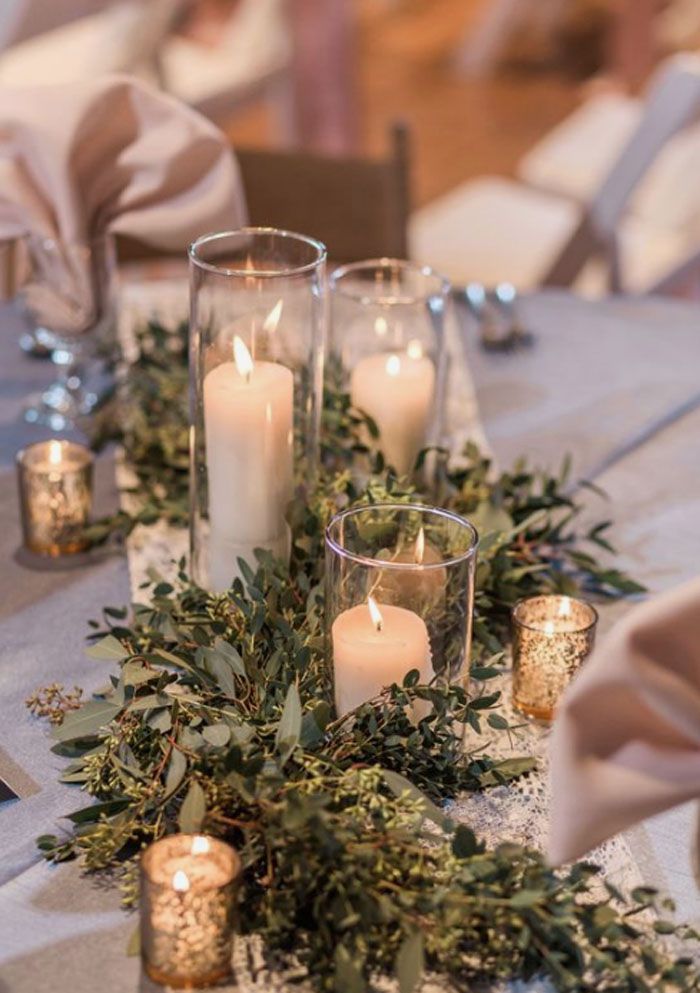 candles and greenery are arranged on the table