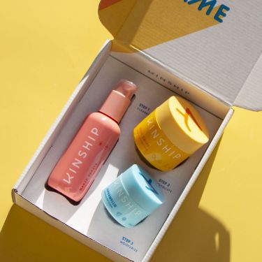 an opened box containing three different types of skin care products on a yellow table top