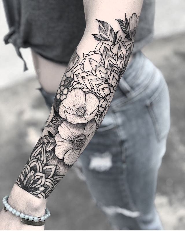 a woman's arm with flowers and leaves tattooed on the left side of her arm