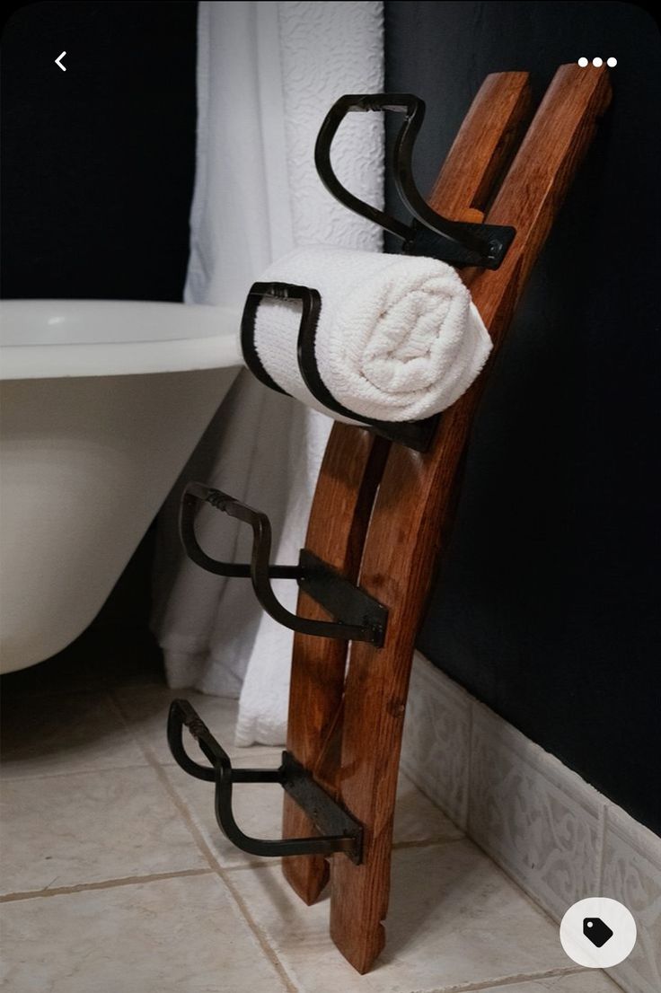 a wooden towel rack with two towels on it next to a bathtub and toilet