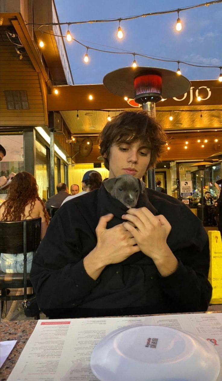 a man sitting at a table holding a cat