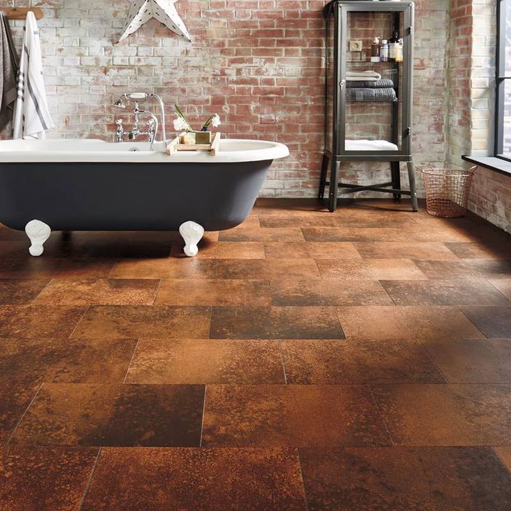 a bath tub sitting next to a brick wall in a room with wooden floors and walls