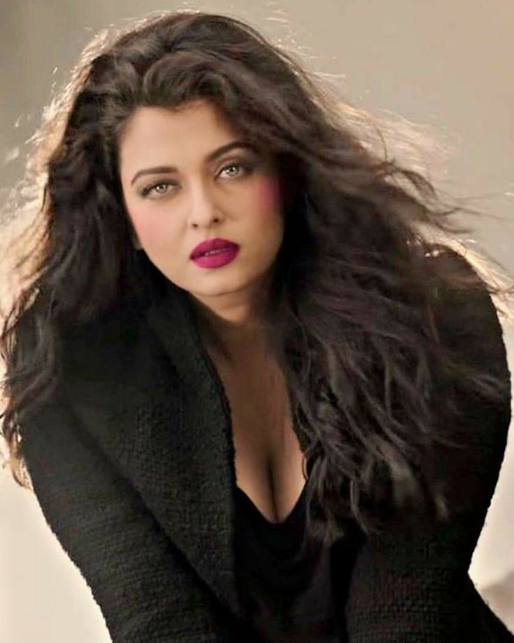 a woman with long dark hair wearing a black jacket and red lipstick on her lips