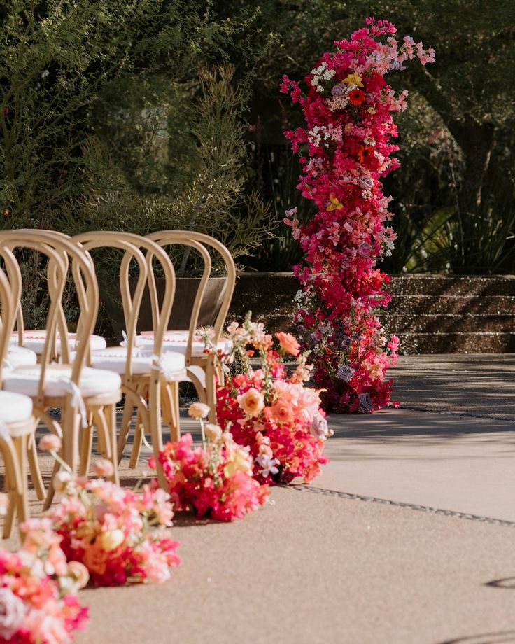 rows of chairs lined up next to each other in front of flowers and greenery