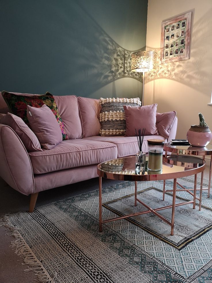 a living room with pink couches and rugs on the floor in front of a blue wall