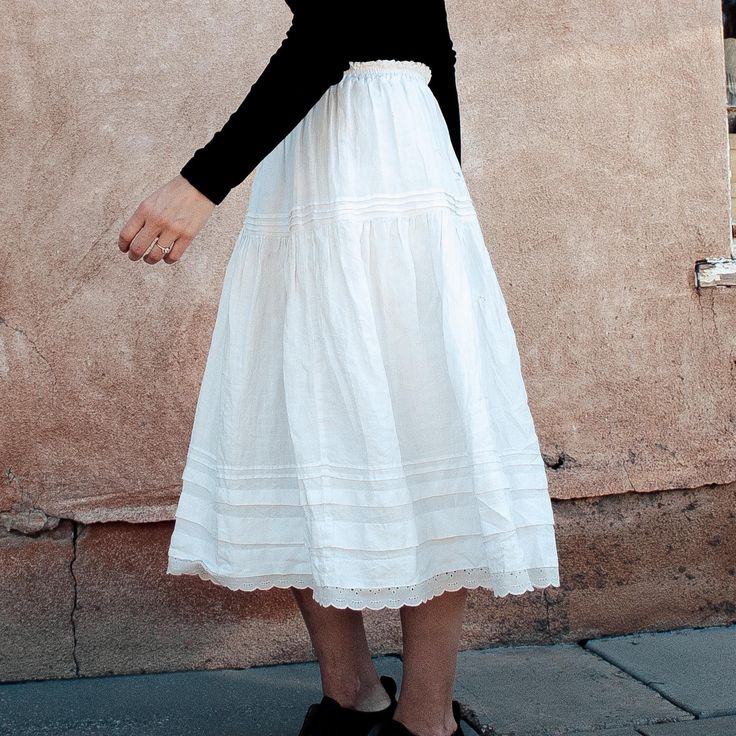 a woman wearing a white dress and black top