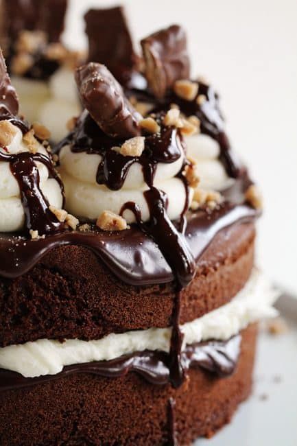 there is a chocolate cake with whipped cream and toppings on the top, topped with nuts